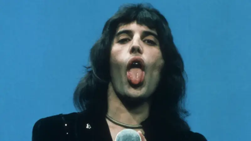 Freddie Mercury z wyciągniętym językiem, śpiewający do mikrofonu. W jego oczach widać pragnienie, by **break free**.