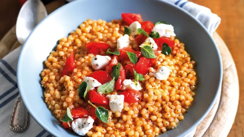Fregola sarda ricetta originale: pasta tostata con pomodorini freschi, mozzarella e basilico, un piatto estivo profumato.