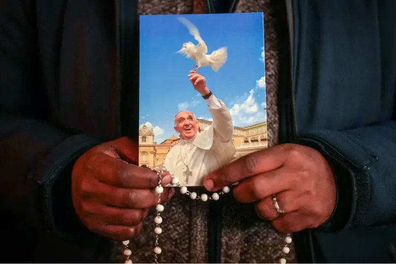 Dłonie trzymają obrazek z Papieżem Franciszkiem wypuszczającym gołębicę. To inspiracja z cytatów papieża franciszka.