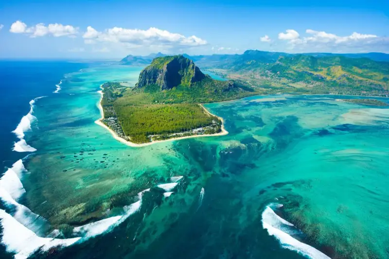 Widok z lotu ptaka na Mauritius: turkusowa laguna, góra Le Morne Brabant i białe fale rozbijające się o rafę. Idealne miejsce na loty na Mauritius.