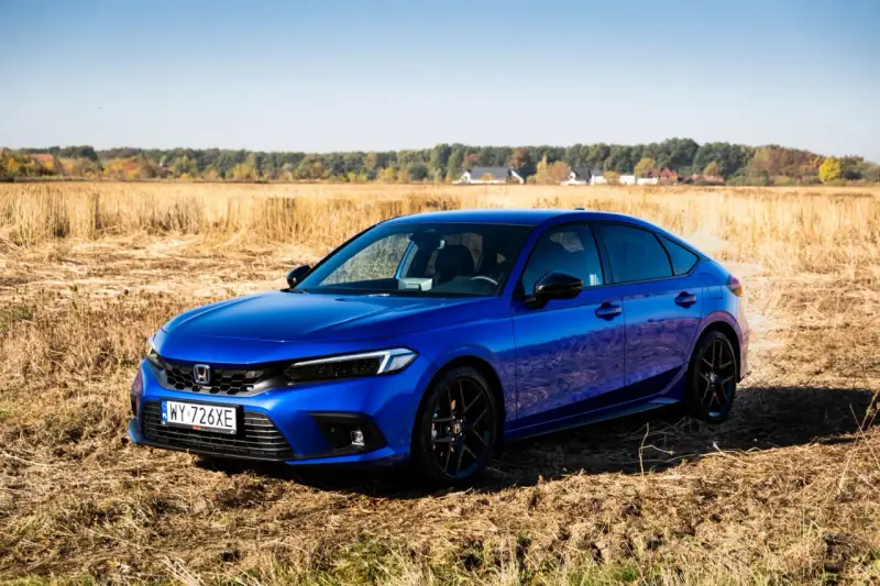 Błękitny Honda Civic 11. generacji na tle jesiennego pola.