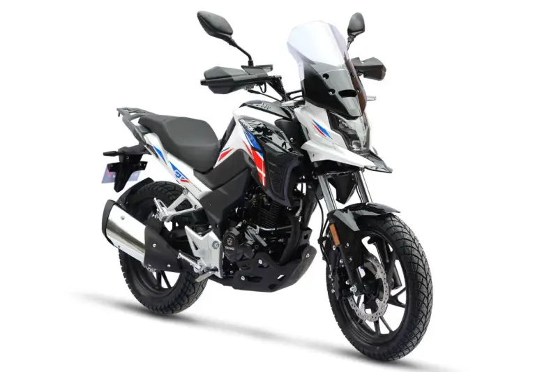 Nowy motocykl gotowy do docierania. Biało-czarny z czerwono-niebieskimi akcentami, z wysoką szybą i terenowymi oponami.