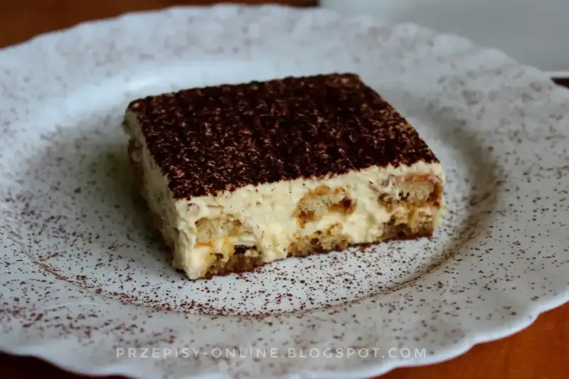 Pyszne tiramisu, czyli zabajone, na białym talerzu, posypane kakao.