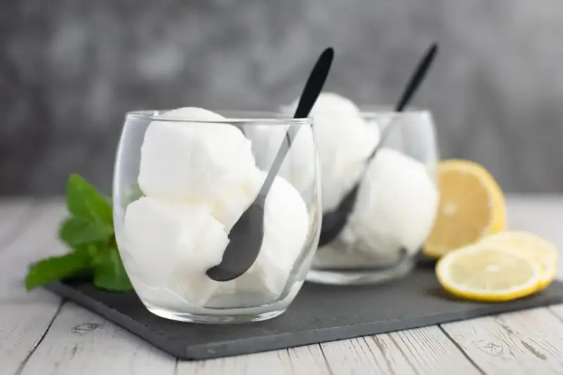 Deux verres de sorbet citron, parfaits pour un cocktail Colonel rafraîchissant, avec des quartiers de citron et de la menthe.