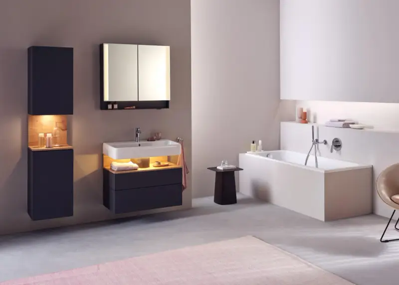 Salle de bain moderne avec baignoire, lavabo et meubles suspendus. Le sol en béton poli et le carrelage mural clair facilitent le nettoyage.