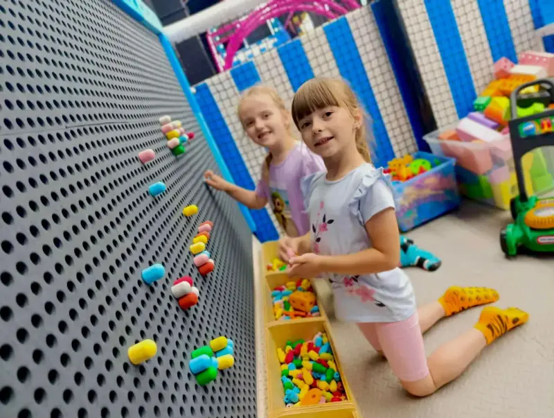Dwie dziewczynki bawią się w sali zabaw. Idealny strój na urodziny do sali zabaw to wygodne ubranie i kolorowe skarpetki.