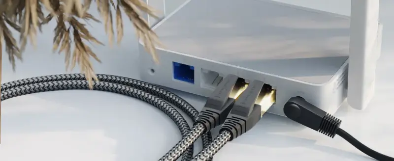 Zwei geflochtene ethernet-Kabel stecken in einem weißen Router, daneben ein schwarzes Stromkabel.
