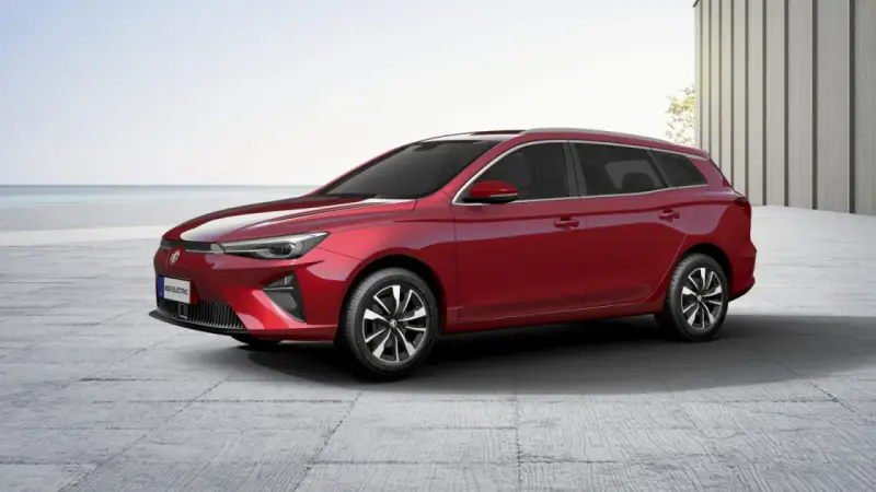 Czerwony MG5 Electric, kombi, stoi na betonowym placu z widokiem na morze.