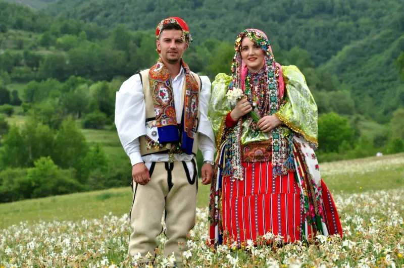 Para w tradycyjnych strojach na tle zielonych wzgórz. Ciekawe albania ciekawostki o kulturze i tradycji.