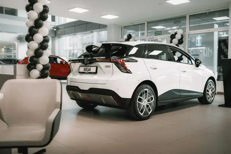 Biały samochód MG4 Electric prezentowany w salonie, ozdobionym czarno-białymi balonami.