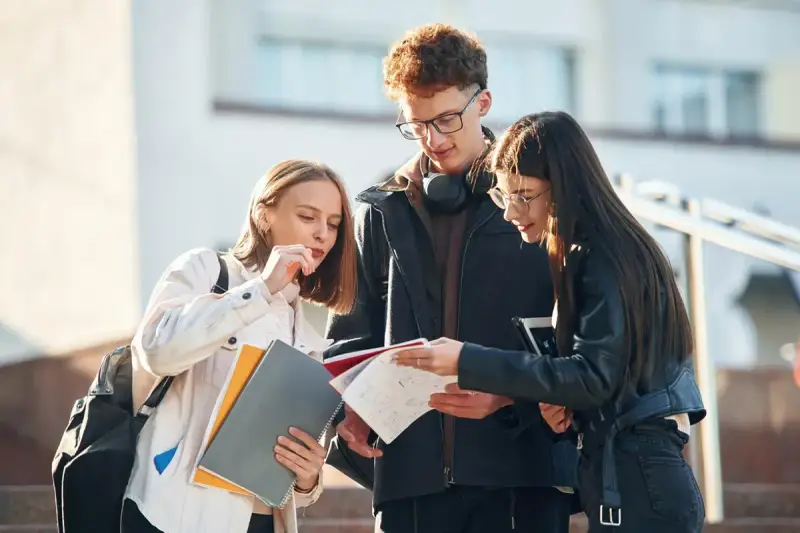 Trzech studentów dyskutuje o notatkach, zastanawiając się nad statusem ucznia a umową zlecenie.