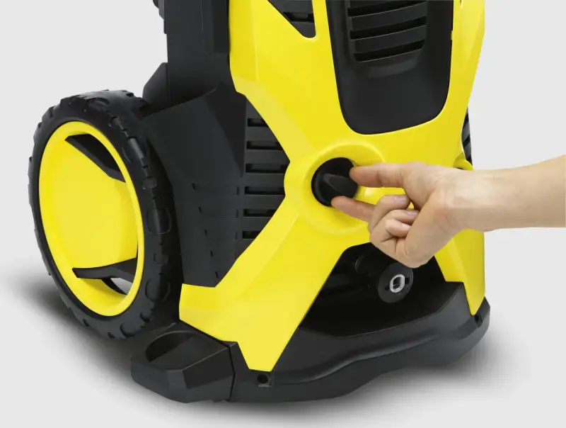 En hand vrider på reglaget på en gul och svart högtryckstvätt, liknande den du hittar till bra kärcher k5 prisjakt.