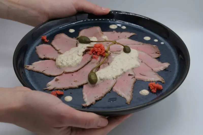 Vitello Tonnato: hauchdünne Scheiben Kalbfleisch, belegt mit cremiger Thunfischsauce, Kapern und roten Kaviar-Kügelchen.