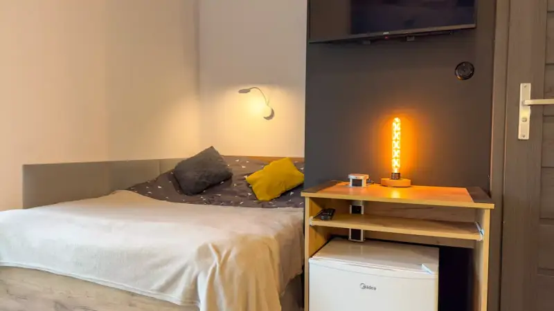 Przytulny pokój z łóżkiem, ozdobną lampą i lodówką. Idealne miejsce na **weekend w Karpaczu**.