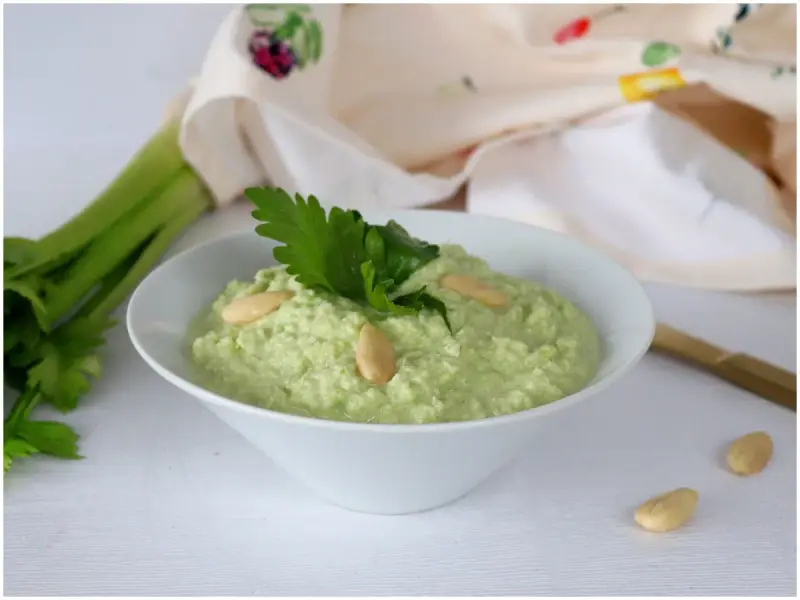 Pesto di sedano fresco, guarnito con mandorle e prezzemolo, pronto per essere gustato.