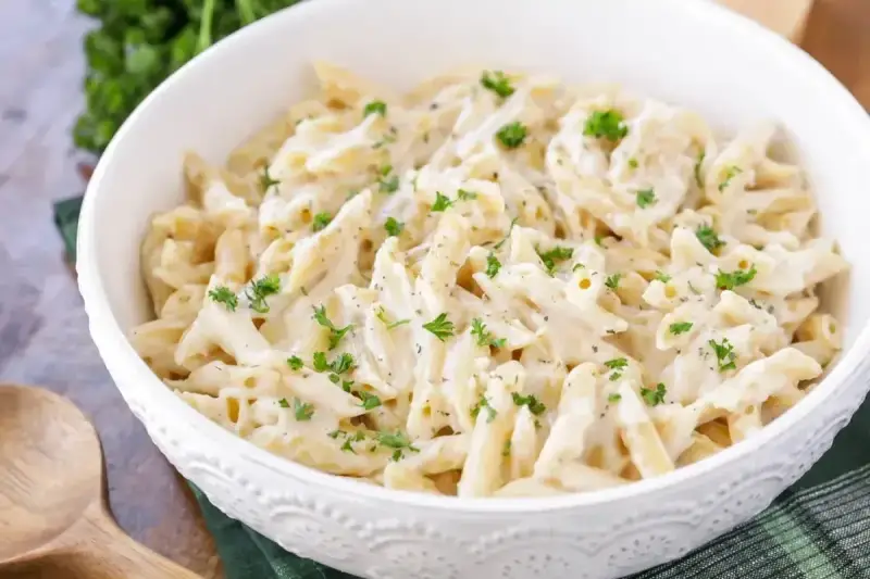 Penne w kremowym sosie śmietanowym, posypane świeżą natką pietruszki. Idealne na szybki obiad.