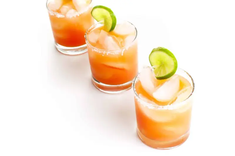 Drei erfrischende Salty Dog Cocktails mit Eis und Limettenspalten, bereit zum Genießen.