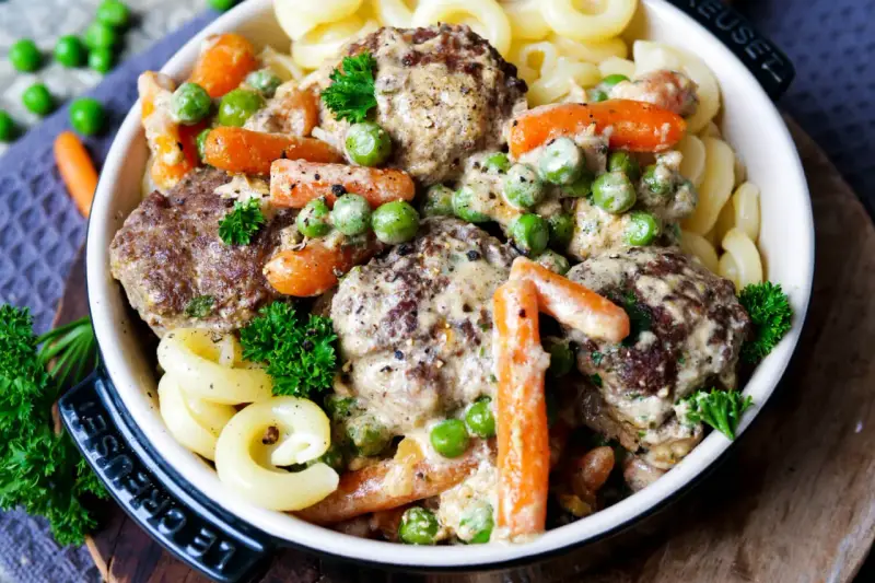 Herzhafte Frikadellen in cremiger Soße mit Erbsen und Möhren, dazu Nudeln. Ein leckeres Wikingertopf Rezept für die ganze Familie.