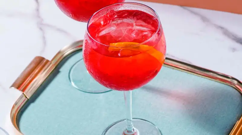 Ein erfrischender Campari Spritz mit Eis und Orangenscheibe auf einem Tablett.