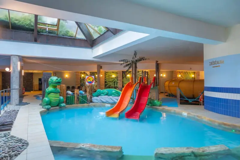 Karpacz hotel z basenem i atrakcjami dla dzieci: zjeżdżalnie, basen, zielone dinozaury i tropikalne dekoracje.