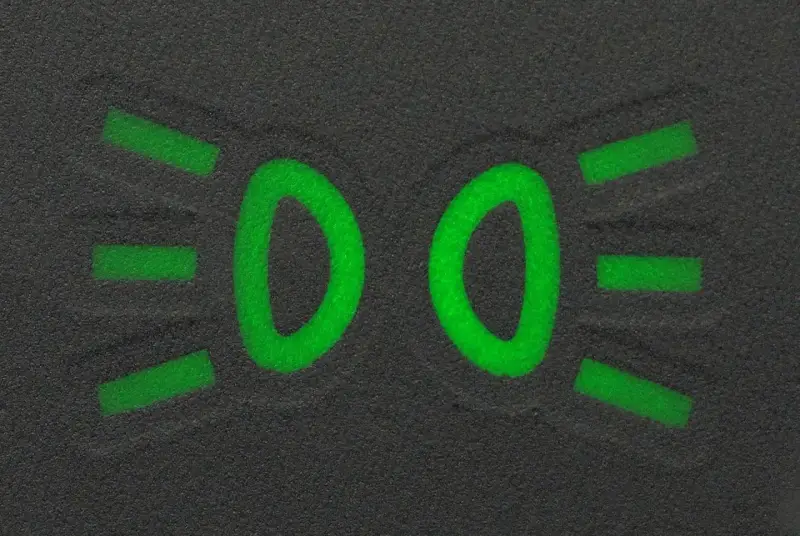 Zielony symbol świateł mijania na ciemnym tle.