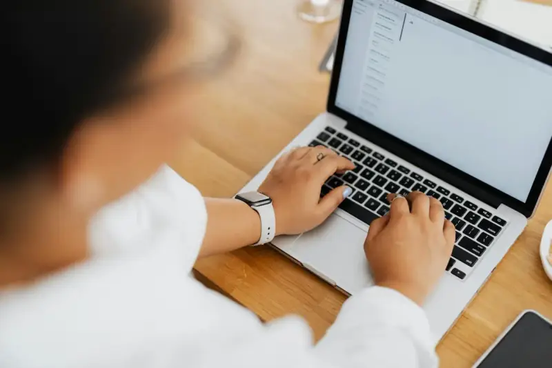 Kobieta pisze na laptopie, na ekranie widać artykuł po niemiecku.