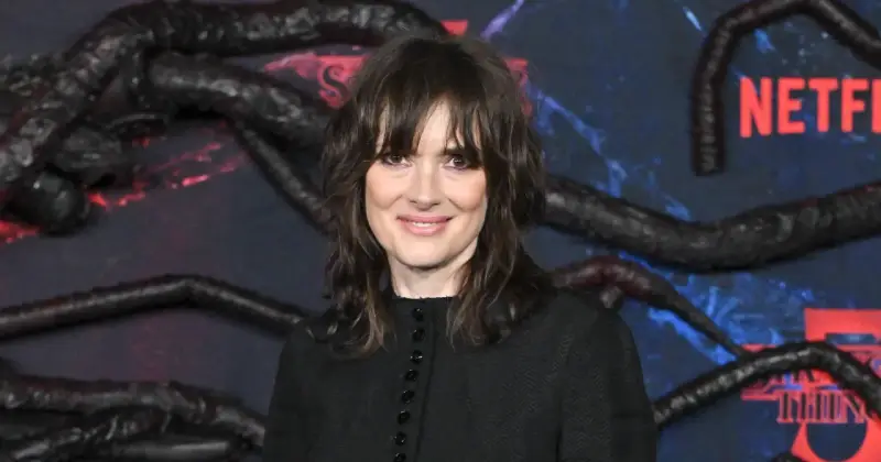 Winona Ryder, gwiazda filmów i seriali, w tym "Stranger Things", na tle dekoracji z mackami i logo Netflix.