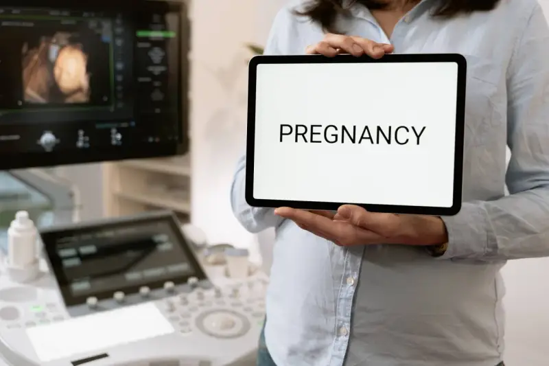 Wczesna ciąża, 2 tydzień. USG pokazuje zarodek, a na tablecie widnieje napis "PREGNANCY".