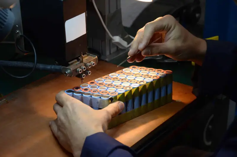 Un technicien assemble des cellules pour comment reparer une batterie de velo electrique. Il utilise un outil de soudure par points.
