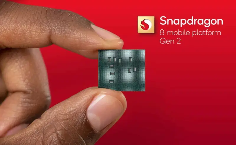 Palec i kciuk trzymają niewielki procesor. Obok widnieje logo Snapdragon 8 mobile platform Gen 2.