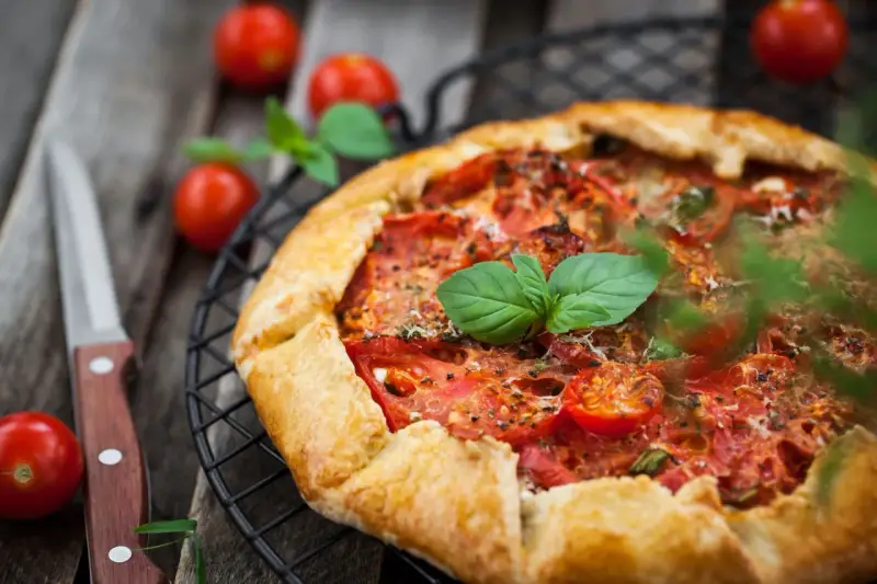 Torta salata con pomodorini freschi e basilico, pronta per essere gustata.