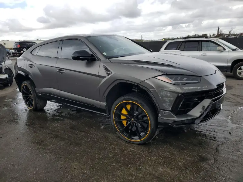 Szary Lamborghini Urus z żółtymi akcentami na felgach, uszkodzony z przodu. Zastanawiasz się nad lamborghini urus cena?