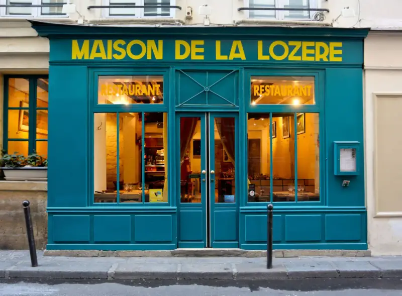 Maison de la Lozère, un ristorante accogliente dove mangiare a Parigi. L'insegna gialla risalta sulla facciata turchese.