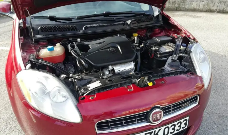 Czerwony Fiat Bravo 1.4 T-Jet z otwartą maską, widoczny silnik i reflektor.