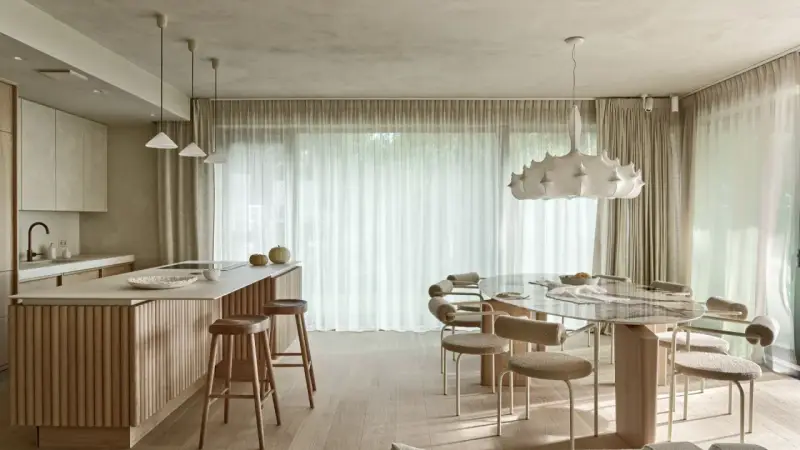 Nowoczesna kuchnia z wyspą i jadalnią. Wnętrze rozświetla designerska lampa wisząca, a całość dopełnia podwieszany sufit.