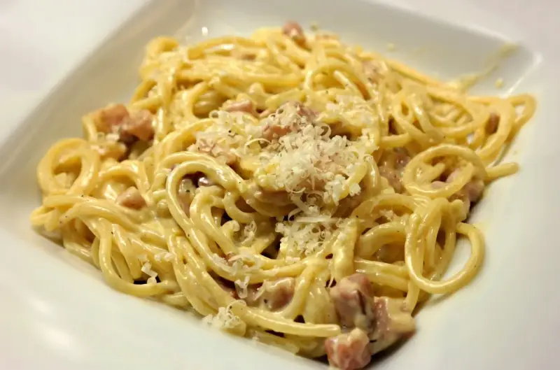 Pyszne spaghetti carbonara z kawałkami boczku, posypane parmezanem. Idealny wybór, jaki boczek do carbonary.