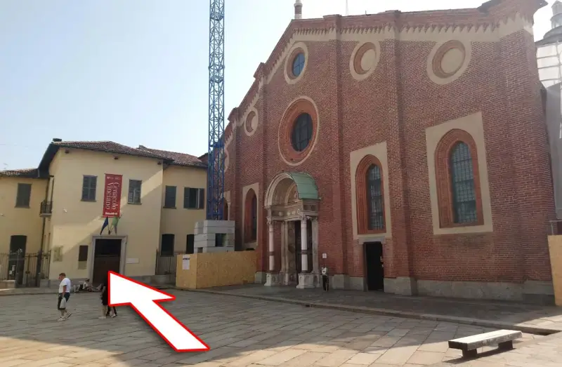 Plac przed kościołem z banerem "Cenacolo Vinciano". Bilety na Ostatnią Wieczerzę można kupić w pobliżu.