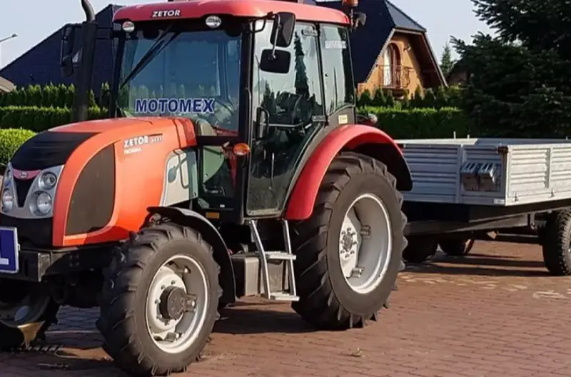 Czerwony Zetor z przyczepą, gotowy do pracy. Marzenie o własnym polu i prawo jazdy na traktor staje się rzeczywistością.