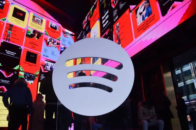 Duże logo Spotify na tle ekranów z podsumowaniami słuchania, w tym informacją o najpopularniejszym artyście na Spotify.