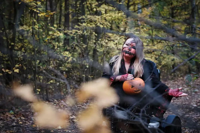 Kobieta w makijażu jack-o'-lantern trzyma dynię, gotowa na noc pełną **horrorów Netflix** w jesiennym lesie.
