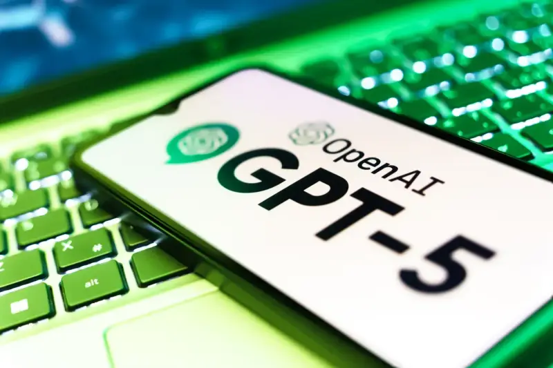 Ekran smartfona z logo OpenAI i napisem GPT-5 leży na podświetlanej zielonej klawiaturze.