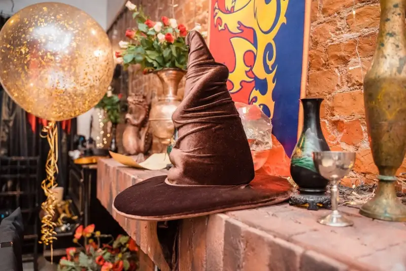 Czapka Mówiąca, złoty balon i bukiet róż tworzą magiczną atmosferę na weselu w stylu Harry'ego Pottera.