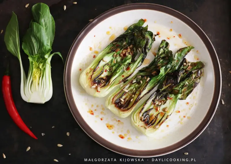 Grillowany pak choi z nasionami słonecznika i papryczką chili na talerzu.