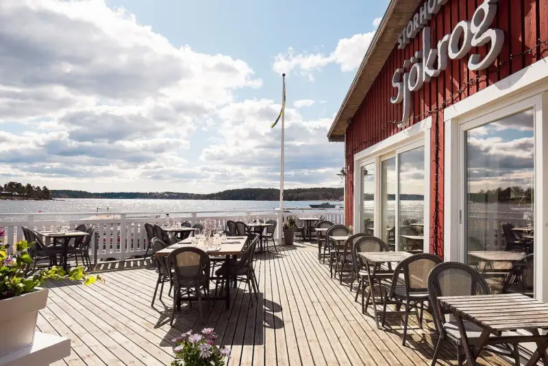 Välkommen till en restaurang vid vattnet i Stockholm! Njut av utsikten över skärgården från en av de många borden på trädäcket.