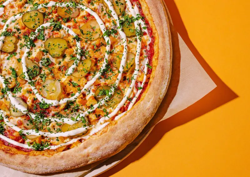 Apetyczna pizza z ogórkiem i sosem, idealna na szybki posiłek. Zastanawiasz się, ile kosztuje pizza we Włoszech?