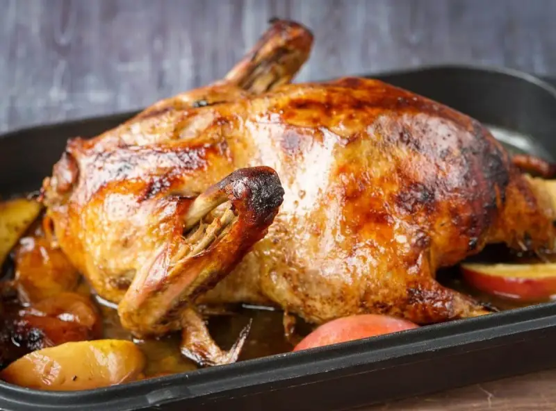 Goldbraun gebratene Ente mit Äpfeln in einer Bratenform. Perfekt zum Ente zubereiten.