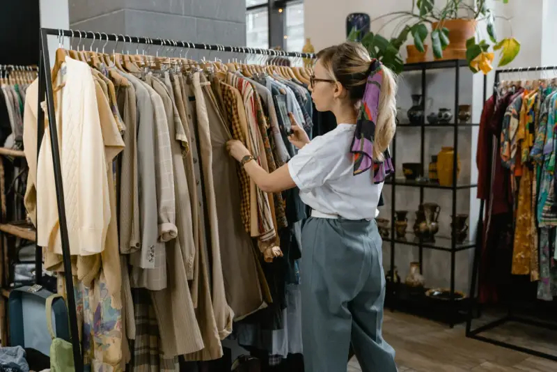 Kobieta przegląda ubrania w sklepie, który wygląda jak **outlet**. Znajduje tam unikatowe perełki.