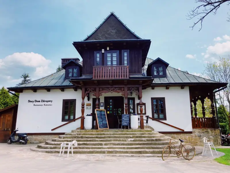Stary Dom Zdrojowy w Beskidach, z charakterystyczną architekturą i kamiennymi schodami, zaprasza do restauracji.
