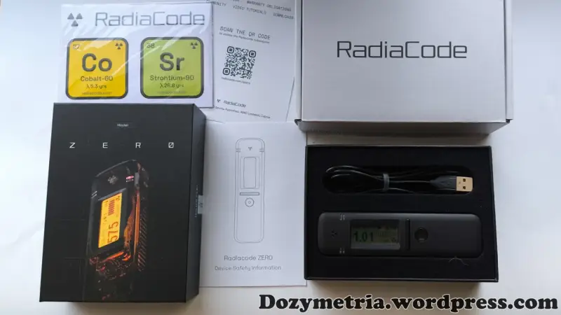 Zestaw Radiacode z dozymetrem ZERO, instrukcją i kablem USB. Obok pudełka z urządzeniem znajduje się karta z informacjami o izotopach Co-60 i Sr-90.