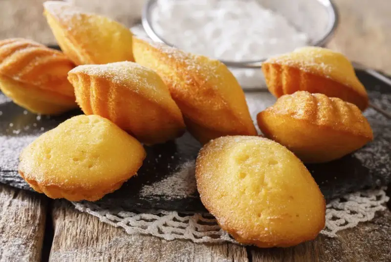 Des madeleines dorées, saupoudrées de sucre glace, prêtes à être dégustées. Une invitation à la recette madeleine parfaite.